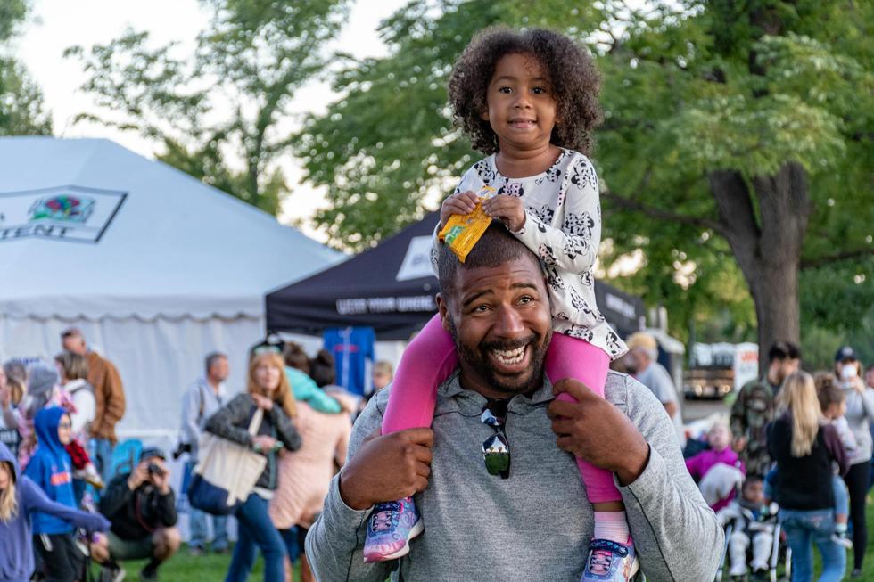 man with young daughter on his shoulders enjoying a festival